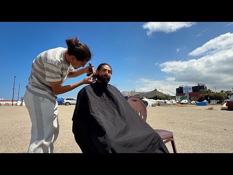 freiwilliger Friseur Beirut – Freiwilliger Friseur schneidet einem vertriebenen Mann im Küstenlager Beirut kostenlos die Haa…