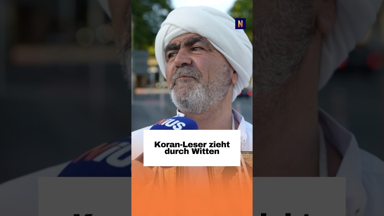 Mann hält mehrere Koran-Exemplare in den Händen auf einer Fußgängerzone in Witten – Koran verteilen im öffentlichen Raum