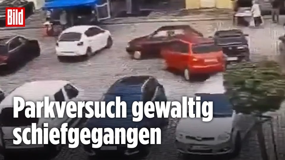 Kleines rotes Auto auf einem Parkplatz in Polen nach missglücktem Einparkmanöver mit beschädigten Fahrzeugen