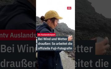 Fuji-Fotografin Megumi Da steht mit Winterjacke und Kamera bei Nebel am Gipfel des Mount Fuji