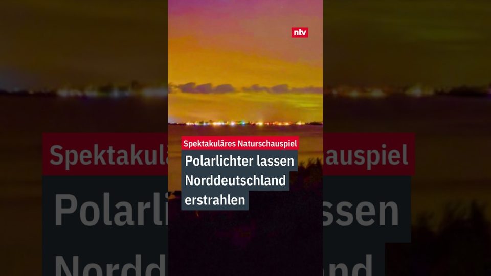 Rötliche und violette Polarlichter leuchten über der Ostseeküste in Norddeutschland