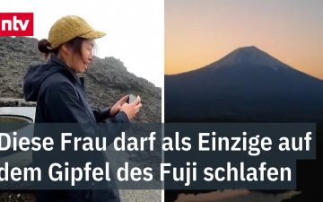 Fuji-Fotografin Megumi Ueda steht im Nebel auf dem Gipfel des Mount Fuji mit Kamera in der Hand