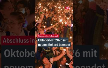 Besucher stoßen mit vollen Maßkrügen beim Oktoberfest 2026 auf der Münchner Theresienwiese an